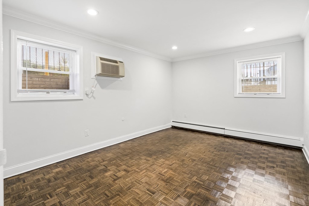 an empty living room with wood flooring and two windows