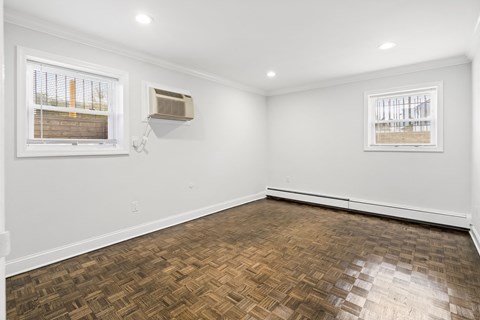 an empty living room with wood flooring and two windows