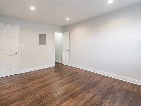an empty living room with wood flooring and white walls