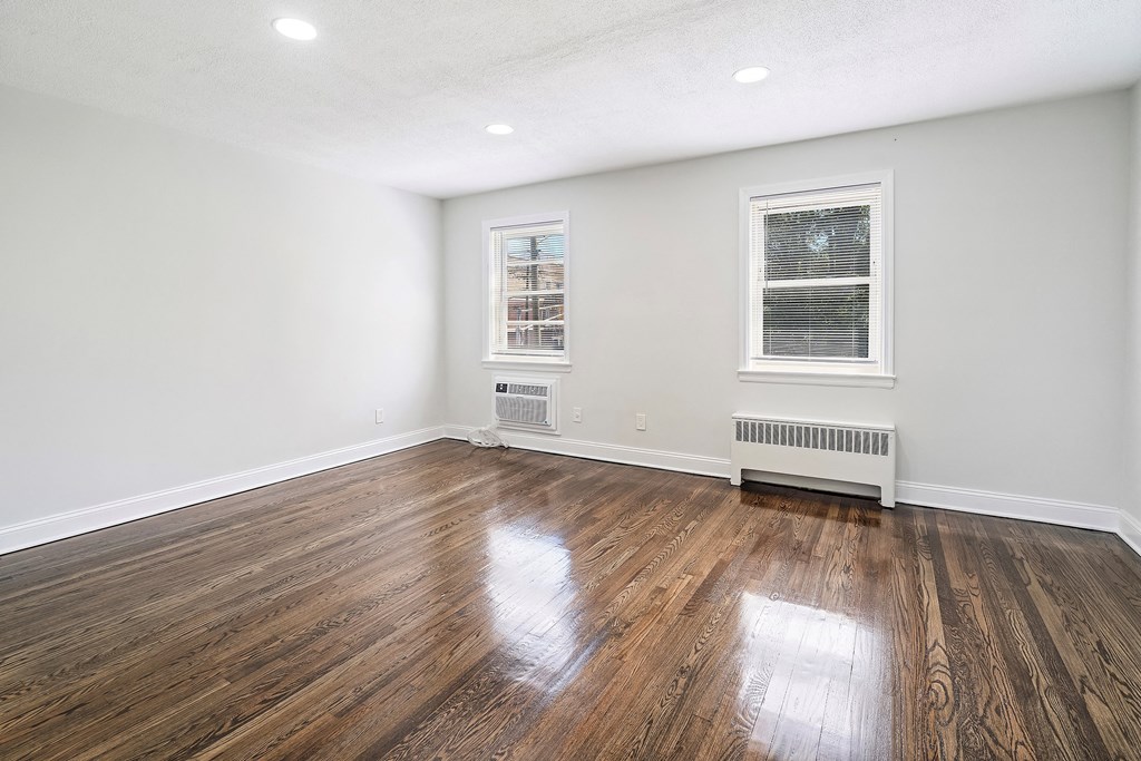 an empty living room with hardwood floors and two windows