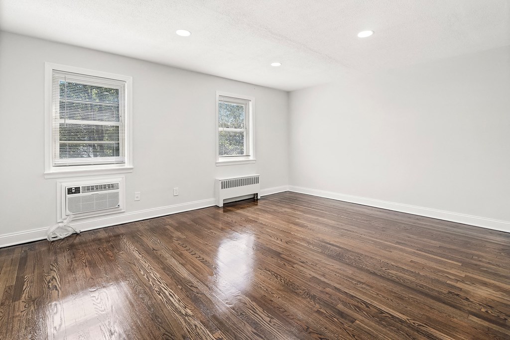 an empty living room with wood flooring and two windows