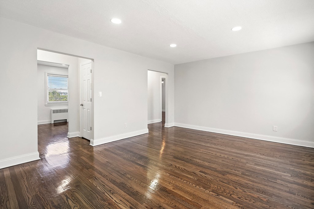 an empty living room with white walls and wood floors