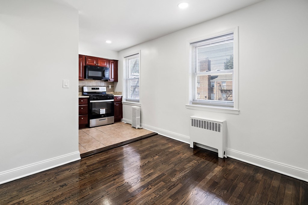 a kitchen with white walls and wood floors and a window