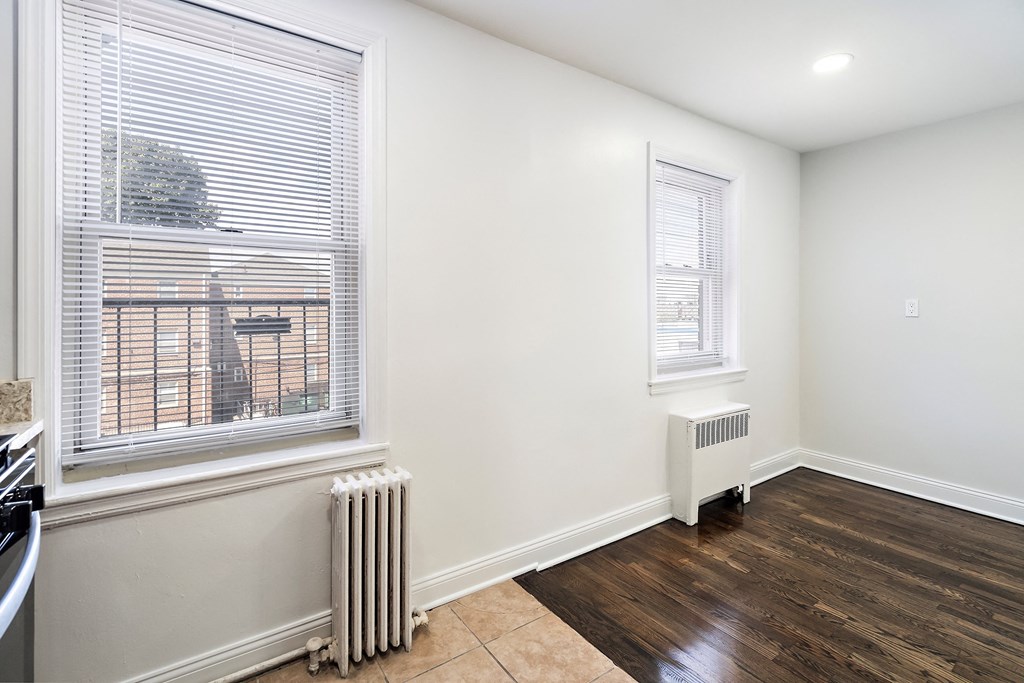 an empty living room with two windows and a radiator