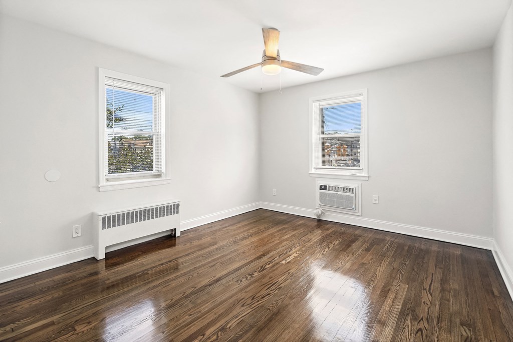 an empty living room with wood floors and a ceiling fan