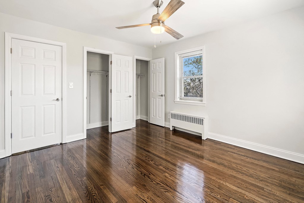 a living room with white walls and a ceiling fan    and a closet