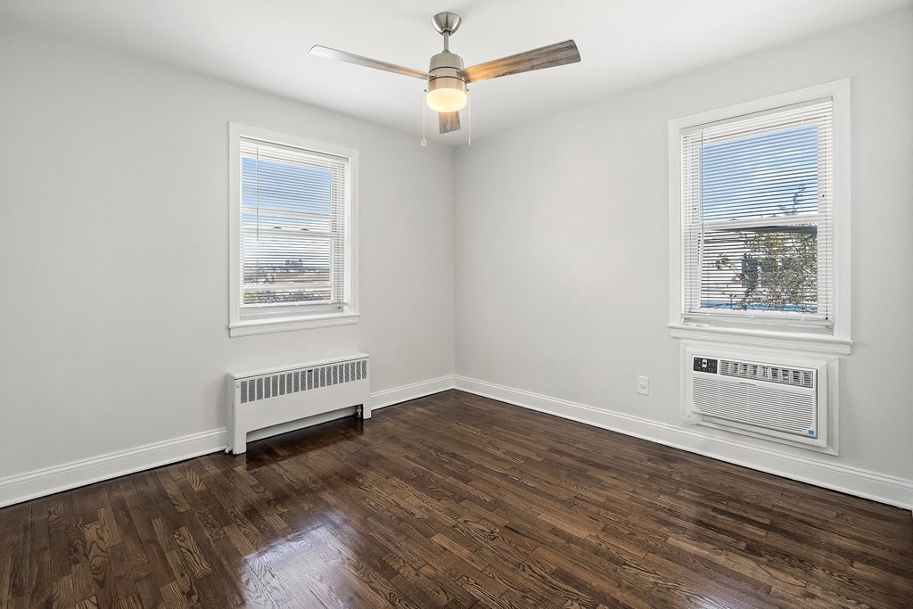 an empty living room with wood floors and a ceiling fan