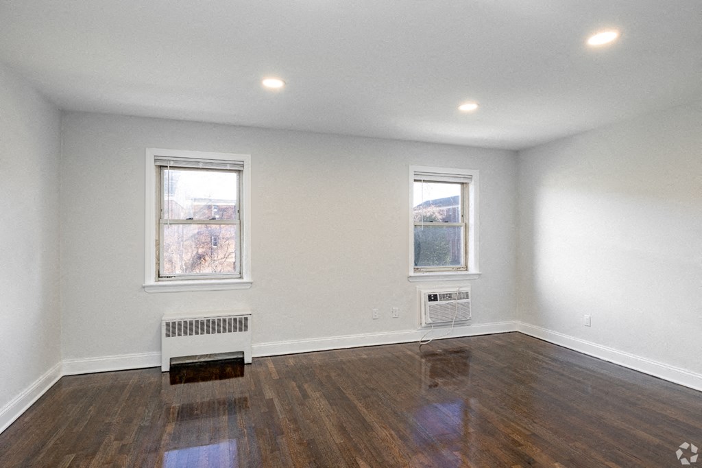 an empty living room with wood floors and two windows