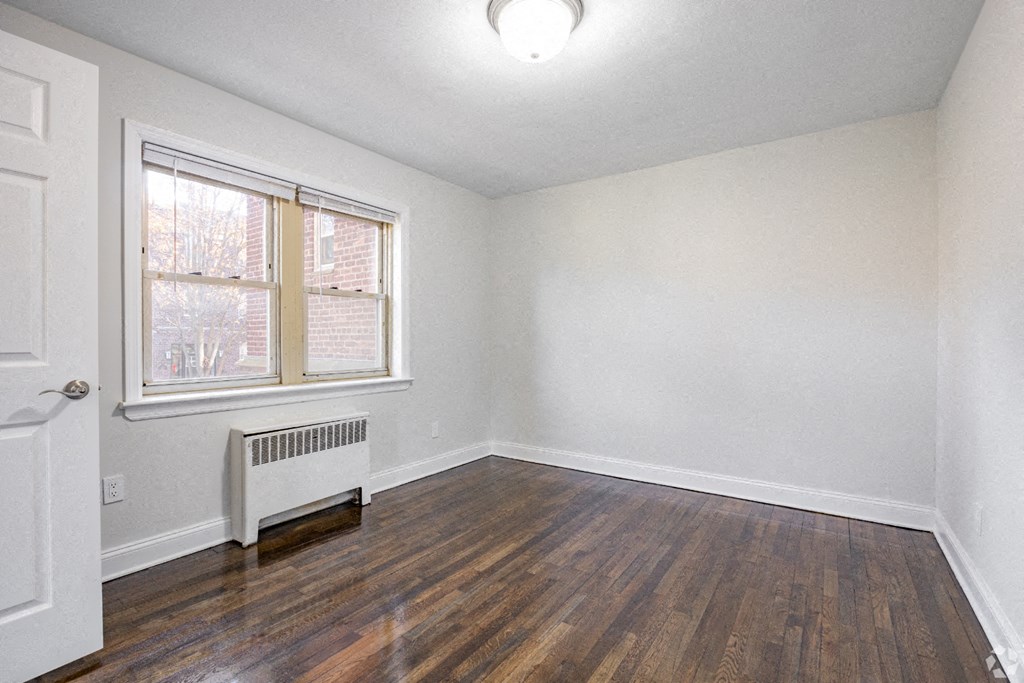 an empty living room with wood flooring and a window