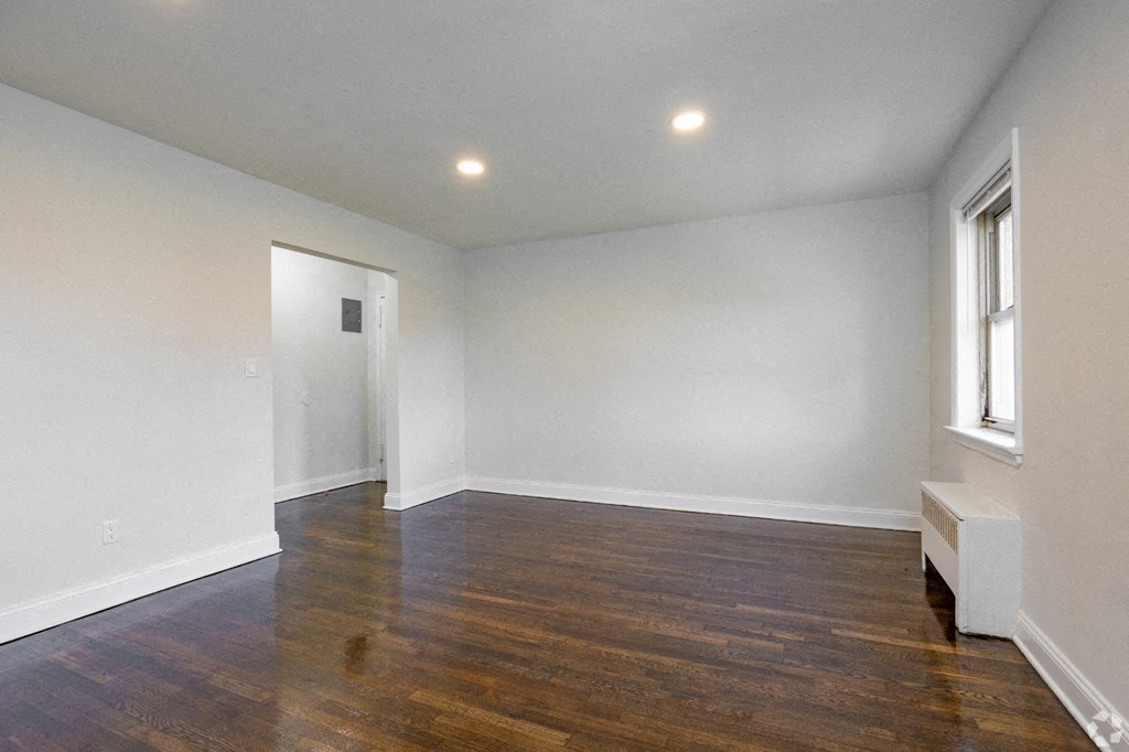 an empty living room with white walls and wood flooring