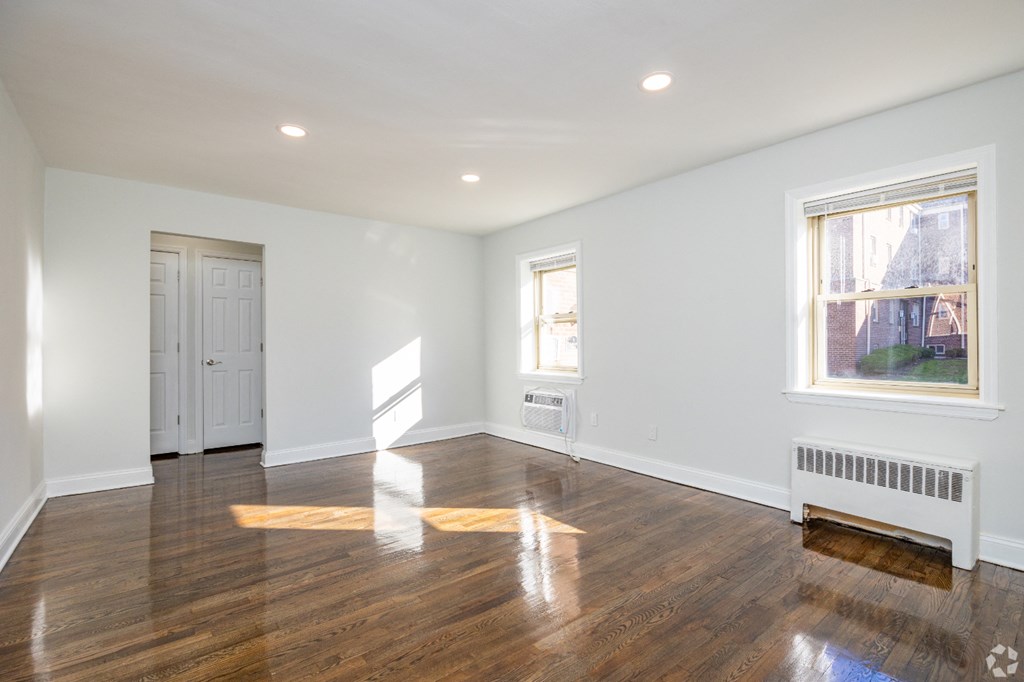 an empty living room with wood floors and white walls