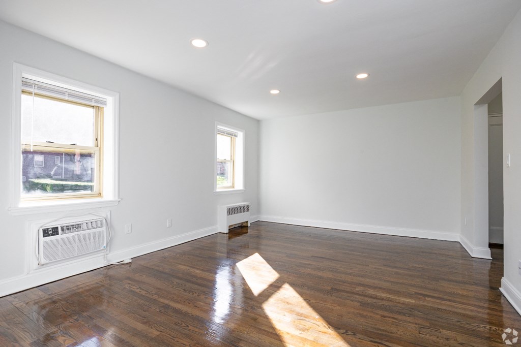 an empty living room with wood floors and white walls