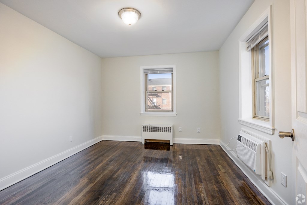 an empty living room with wood floors and a window
