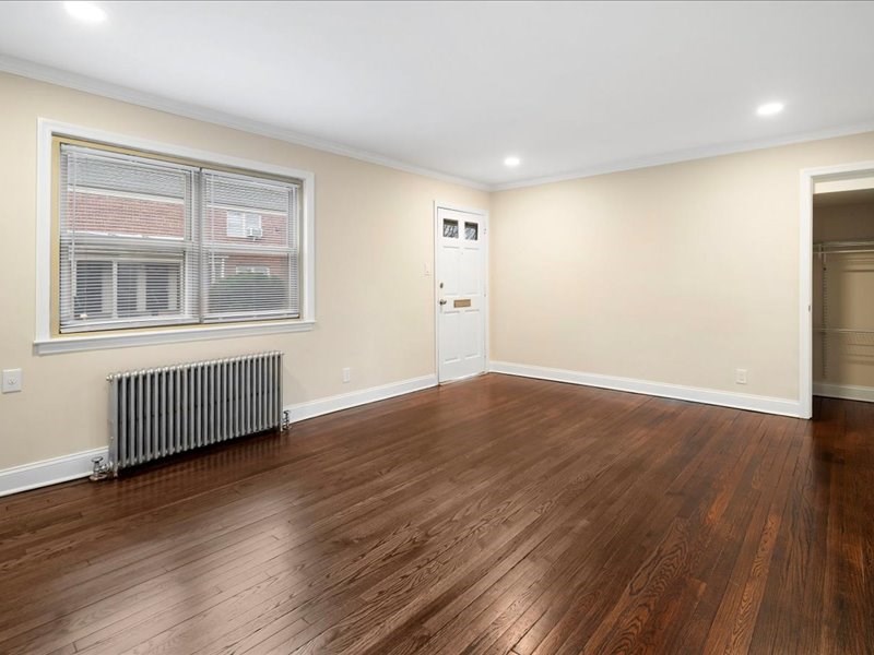 A room with wooden flooring and a window with blinds.