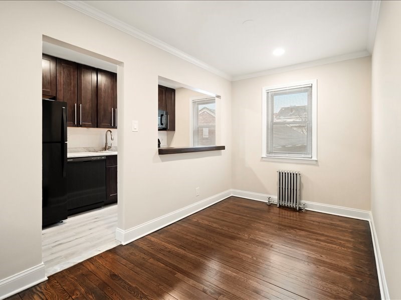 A room with wooden floors and a black fridge.