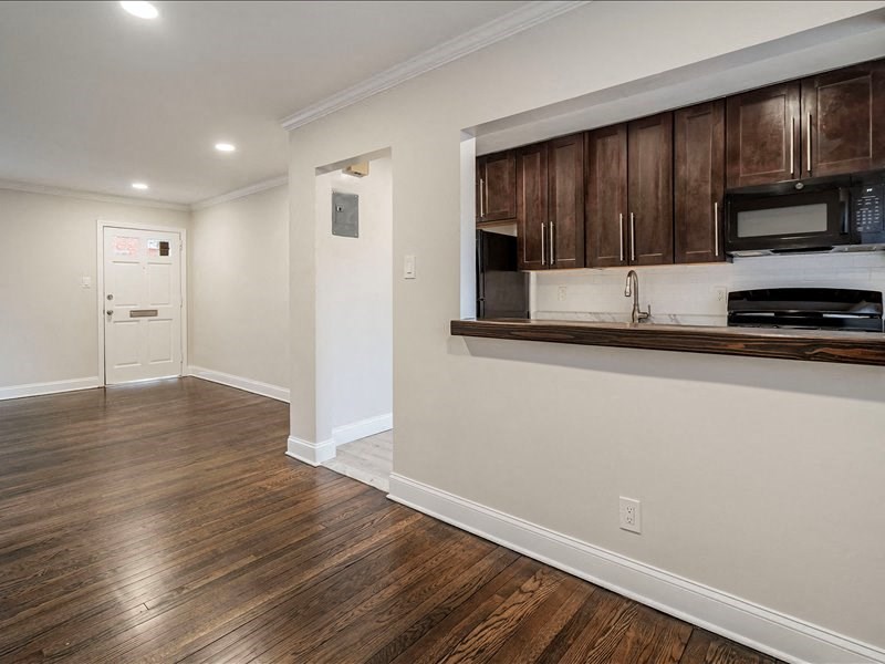 A kitchen with dark wood cabinets and a white wall.