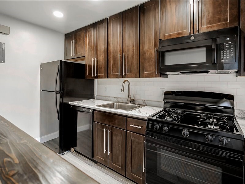 A kitchen with black appliances and wooden cabinets.