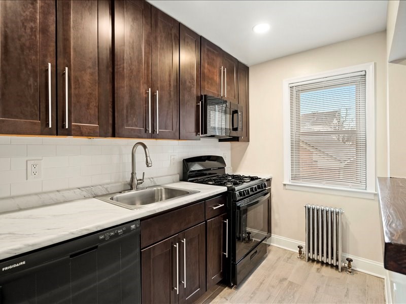 A kitchen with dark wood cabinets and black appliances.
