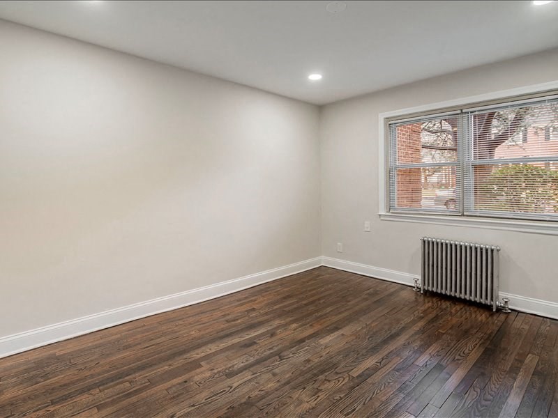 A room with wooden floors and a window with blinds.