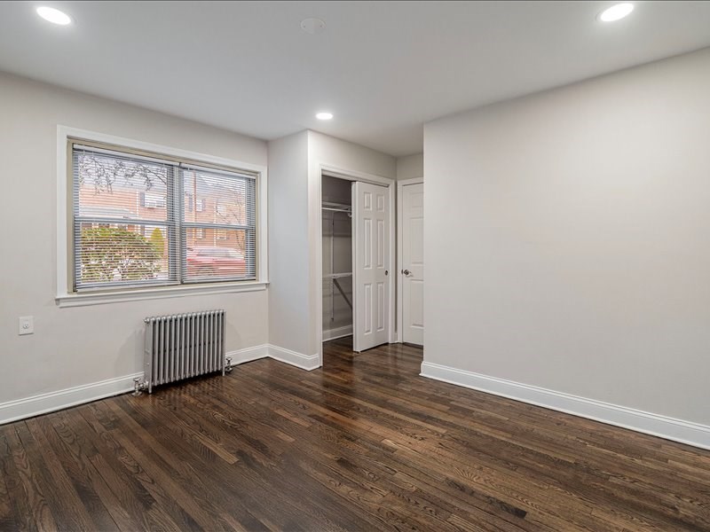 A room with wooden floors and a window with a view of a building.