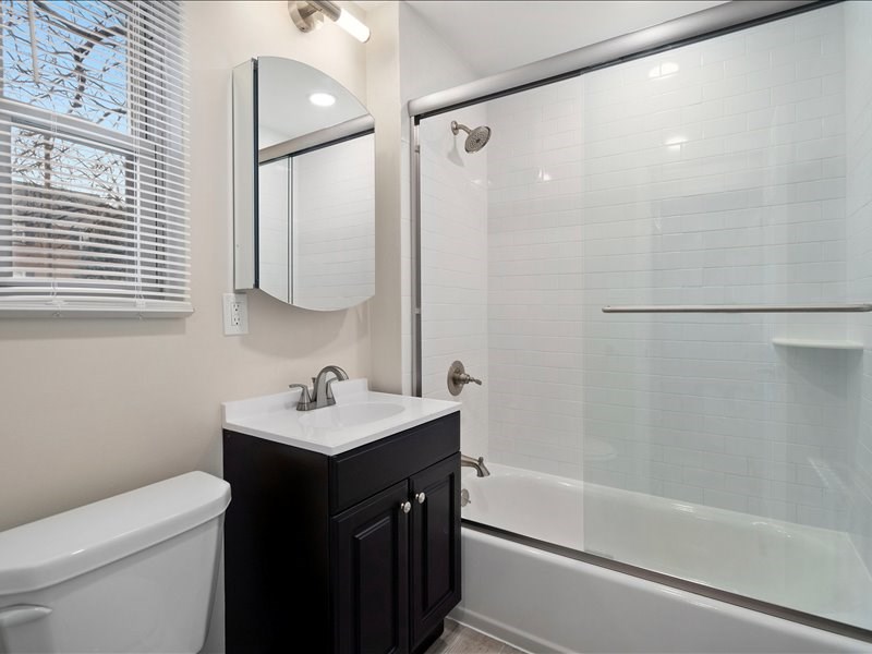 A bathroom with a white tub, sink, and a mirror.