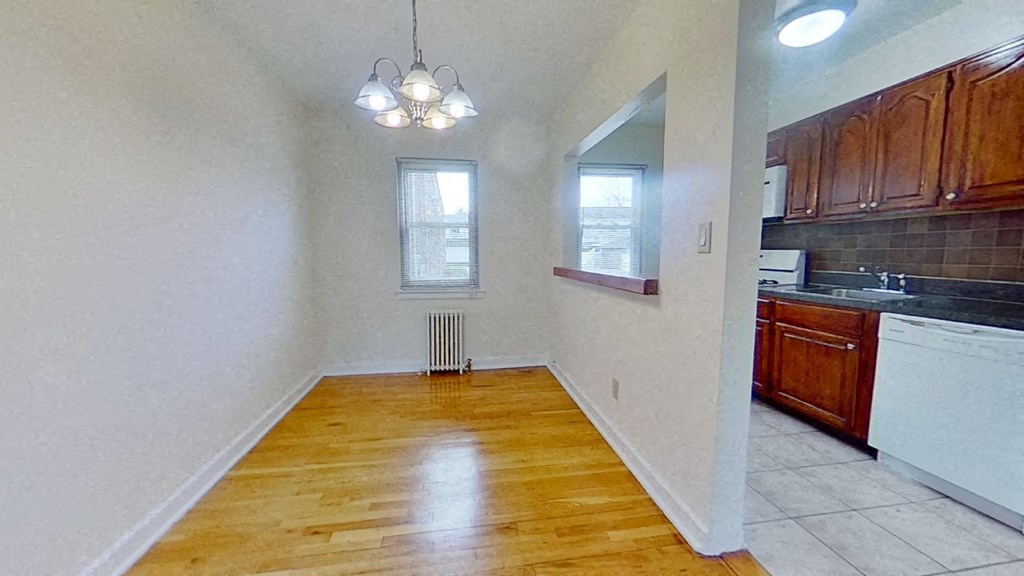 an empty kitchen and dining room with wood flooring and a window