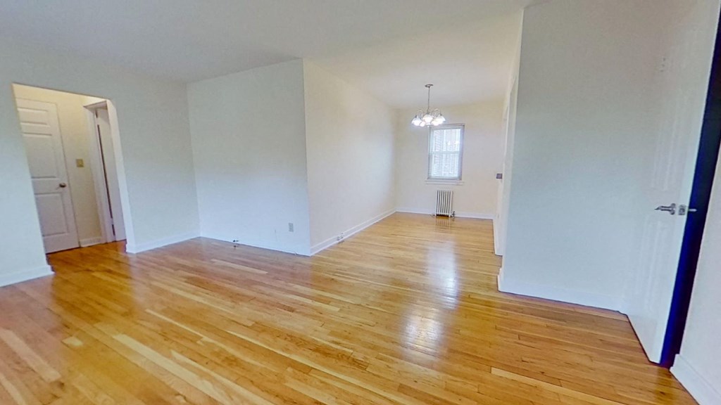 an empty living room with a hard wood floor and white walls