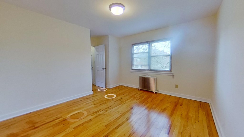 an empty living room with wood floors and a window