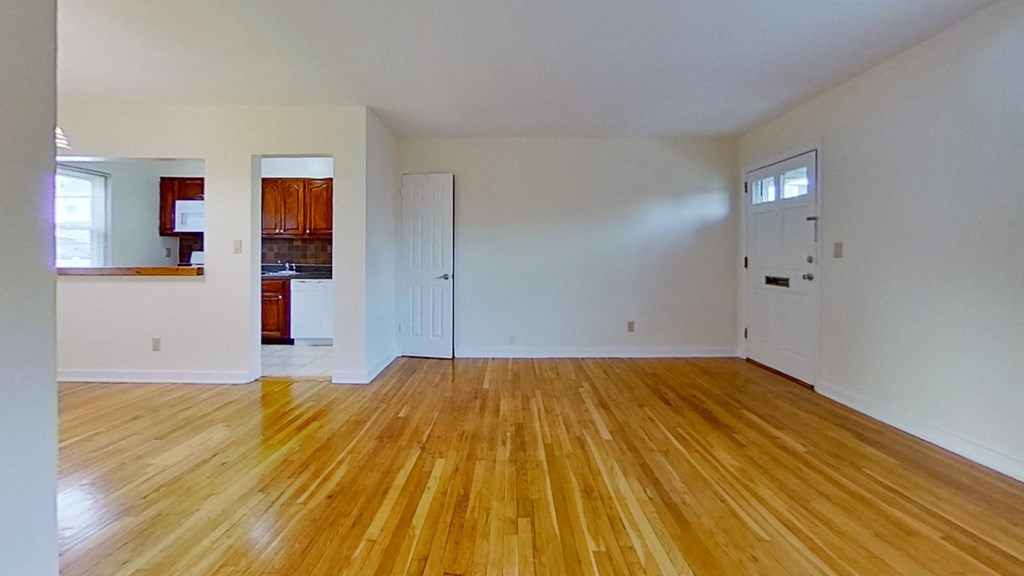 an empty living room with wood floors and white walls