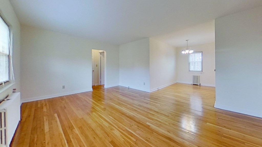an empty living room with wood floors and white walls