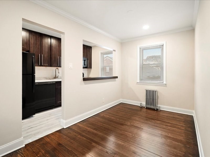 A kitchen with dark wood cabinets and a black refrigerator.