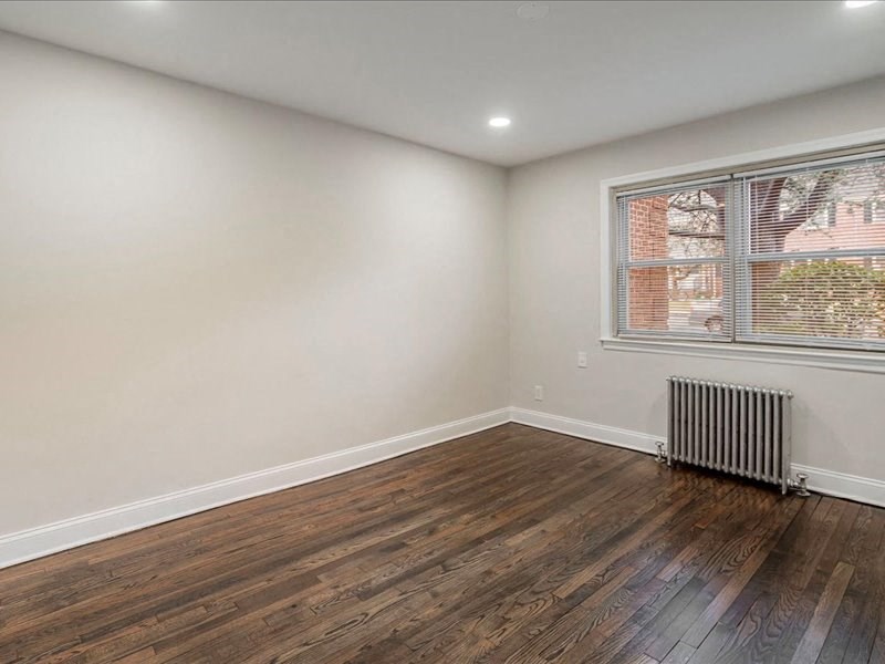 A room with wooden floors and a window with a view of a building outside.
