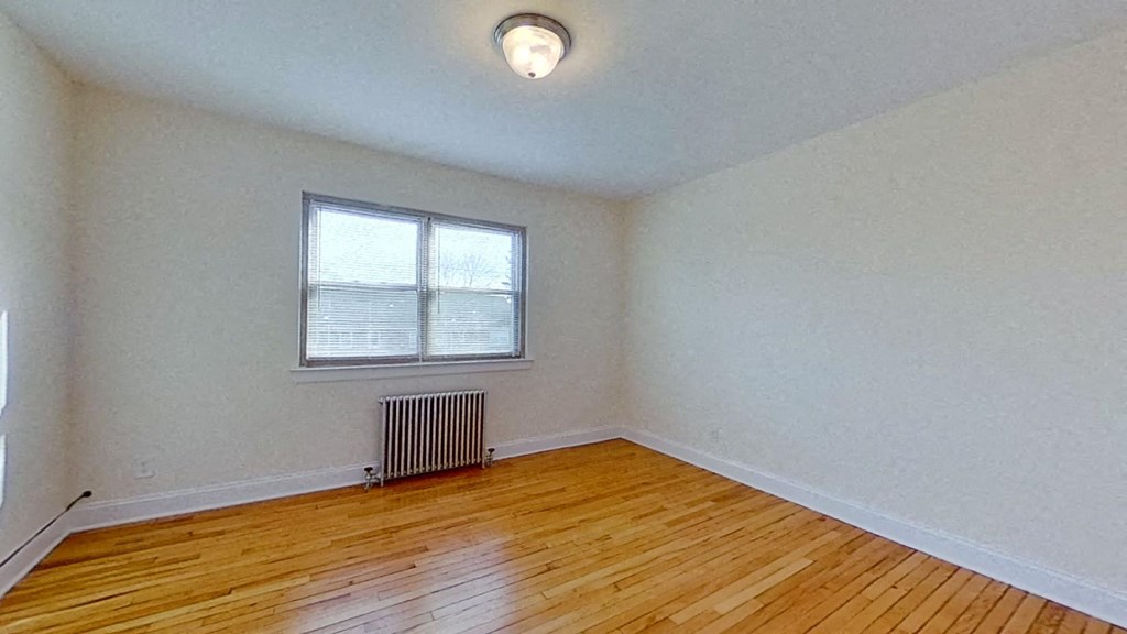 an empty living room with wood floors and a window