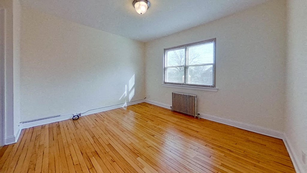 an empty living room with wood floors and a window