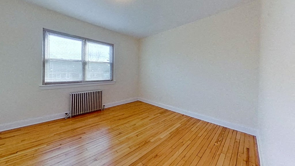 an empty room with wood floors and a window