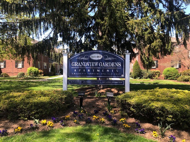 a sign in front of a yard with flowers
