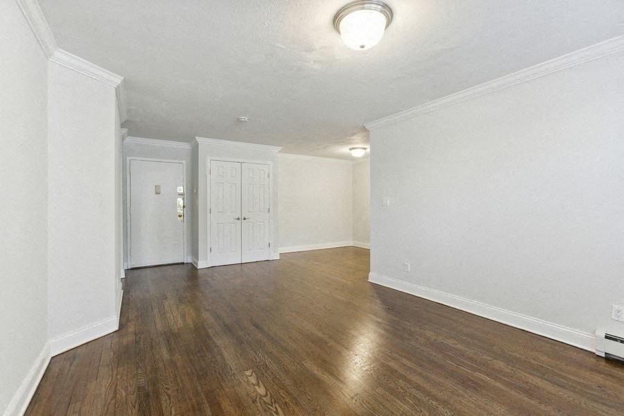 an empty living room with wood floors and white walls