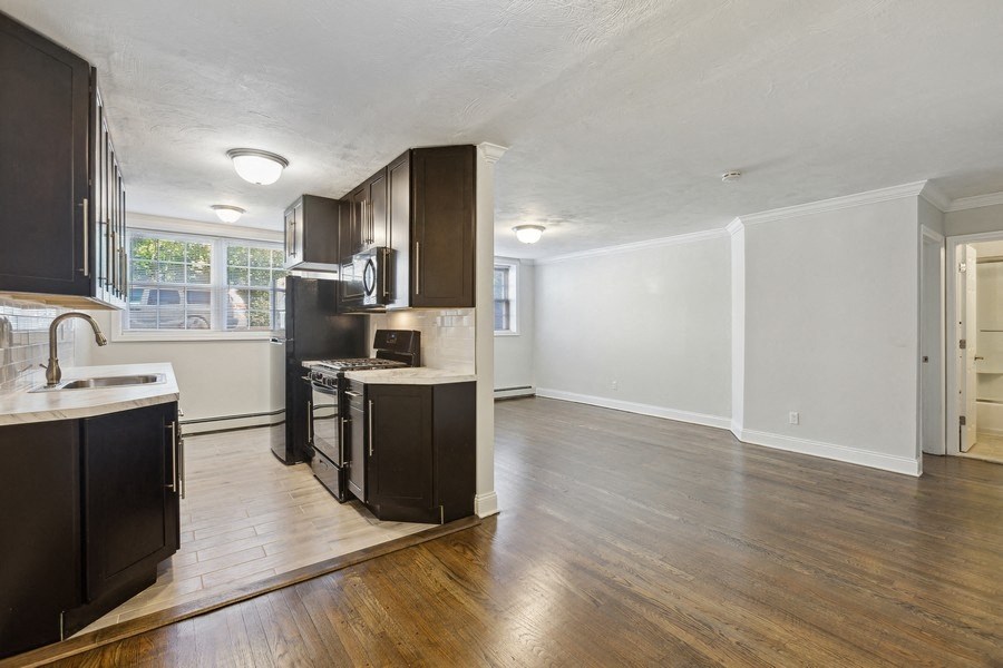 an empty kitchen and living room with wood flooring and dark cabinets