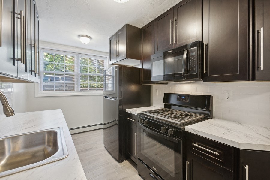 a kitchen with black cabinets and stainless steel appliances and a sink