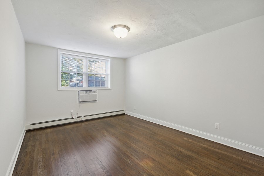 an empty living room with wood floors and a window
