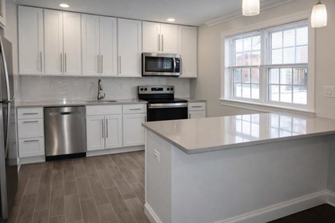 A kitchen with white cabinets and a stainless steel refrigerator.