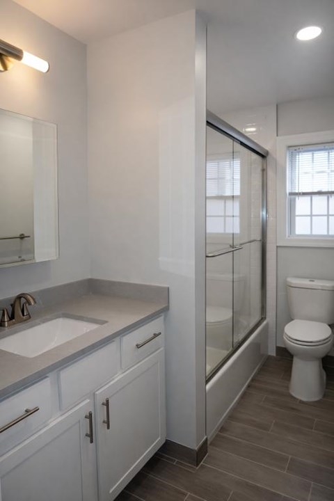 A white bathroom with a toilet, sink, and mirror.