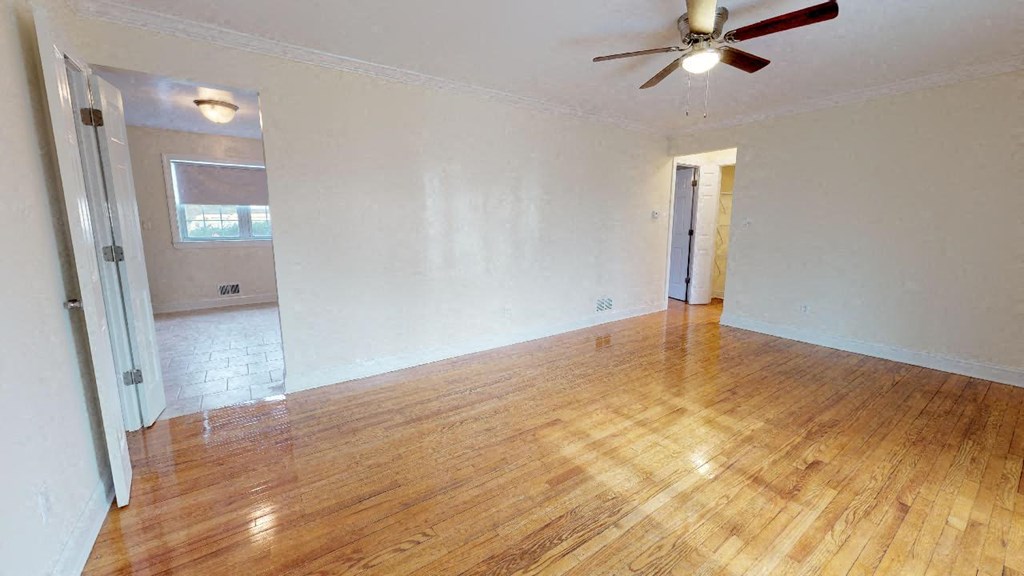 an empty living room with a ceiling fan and wood floors