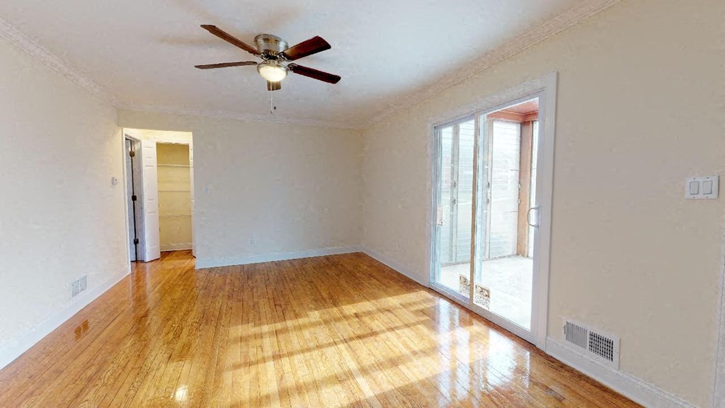 an empty living room with a ceiling fan and a window