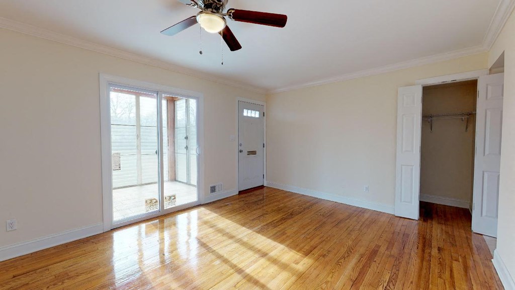 an empty living room with wood floors and a ceiling fan