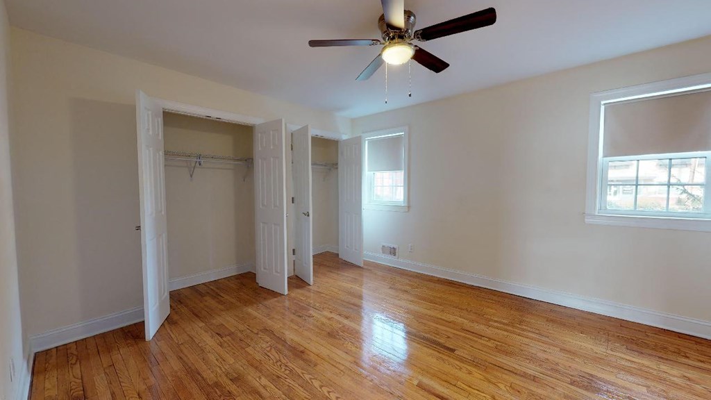 an empty bedroom with a ceiling fan and a closet