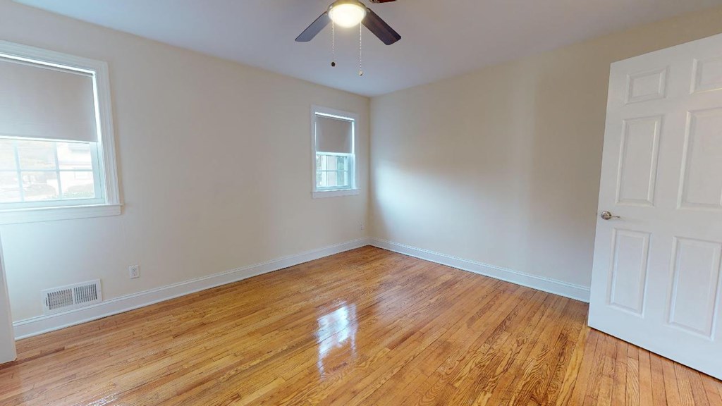 a living room with a wooden floor and a ceiling fan