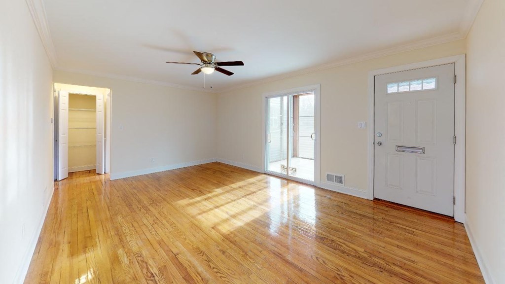 an empty living room with a ceiling fan and a door