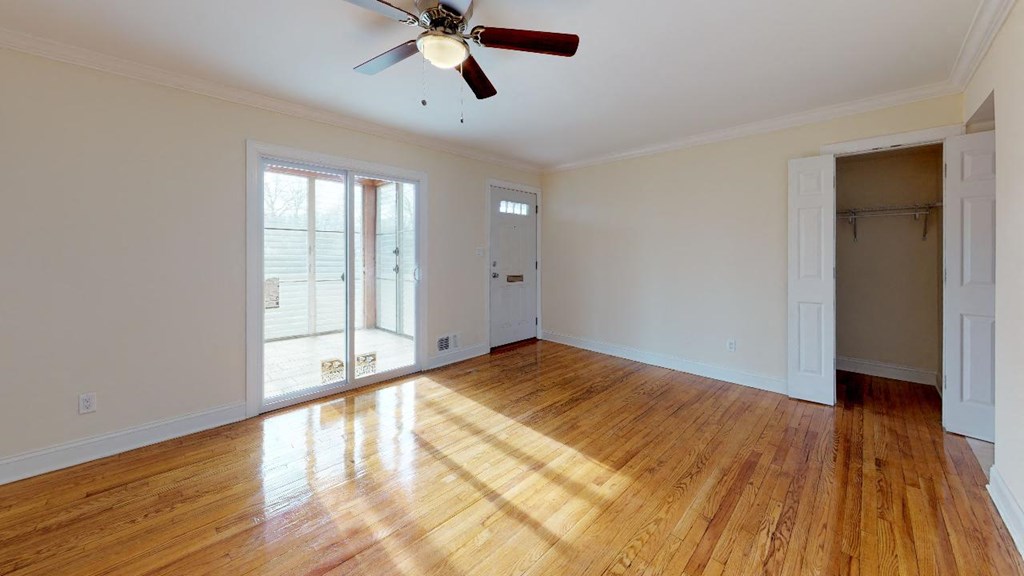 an empty living room with wood floors and a ceiling fan
