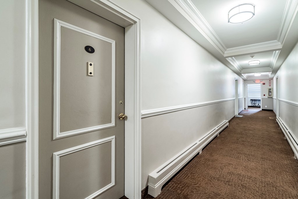 a hallway with white walls and white doors and a brown carpet
